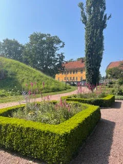 Trädgården med häckar och blommor framför Slottet